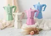 Four Bialetti Moka Express coffee makers in pastel colors (green, cream, pink, blue) arranged on a surface with draped fabric and dried flowers. Anteprima dell’immagine prodotto
