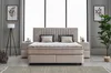 A bedroom scene featuring a beige boxspring bed with a headboard, two nightstands, a floor lamp, and artwork on the wall. Produktbild-Vorschau