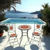 A mosaic garden set for two people is placed on a patio overlooking a pool and a scenic ocean view. Voir les images du produit