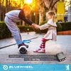 Two young girls are holding hands while one stands on a hoverboard, with a sunny outdoor background. Produktbild-Vorschau