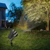 A solar-powered spotlight illuminates a tree in a garden at dusk. Produktbild-Vorschau