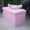 A person's feet resting on a pink storage ottoman in a living room setting. Náhled obrázku produktu