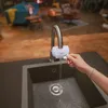 A hand is shown adjusting a BRITA water filter attached to a kitchen faucet, with water flowing into a sink. Produktbild-Vorschau