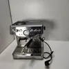 A silver espresso machine with a black portafilter is placed on a white surface against a light gray background. Produktbild-Vorschau