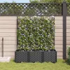 A garden scene with a planter box filled with flowering vines against a wooden fence. Anteprima dell’immagine prodotto