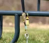 A close-up of a ratchet strap attached to a metal bar, with grass in the background. Podgląd zdjęcia produktu