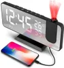 A digital alarm clock with a projected display and a smartphone charging on its base. Náhled obrázku produktu