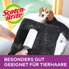 A person is using a lint roller on a black pillow covered in pet hair, with a beagle dog in the background. Produktbild-Vorschau