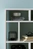 A white shelf unit with various decorative items and books. Náhled obrázku produktu