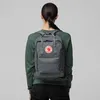 A person wearing a green sweatshirt and black pants is seen from the back, wearing a gray Fjällräven Kånken backpack. Produktbild-Vorschau