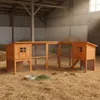 A wooden rabbit or chicken coop is set up on a bed of straw inside a barn. Produktbild-Vorschau