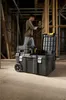 A man is using a power tool while standing on top of a large black toolbox with wheels. Another smaller toolbox is stacked on top of the large one. The scene appears to be an unfinished construction site. Anteprima dell’immagine prodotto