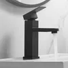 A black bathroom faucet with water running into a sink. Podgląd zdjęcia produktu