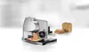 A metal meat slicer with a blade and a tray, with slices of meat on the tray, and some bread next to it on a white and gray background. Anteprima dell’immagine prodotto