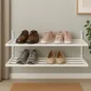 A two-tiered white shoe rack mounted on a light gray wall, displaying various types of shoes. Produktbild-Vorschau