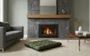 A living room scene with a fireplace, sofa, and a floor cushion. Anteprima dell’immagine prodotto