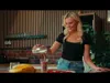 A woman in a kitchen pouring a smoothie into a glass. Produktbild-Vorschau