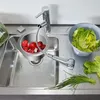A kitchen sink with a faucet, a colander of lettuce, tomatoes in a sink insert, and chives. Náhled obrázku produktu
