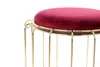 A close-up of a stool with a red velvet seat and gold legs. Produktbild-Vorschau