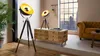 A modern living room with industrial-style decor, featuring tripod floor lamps and a pallet coffee table. Podgląd zdjęcia produktu