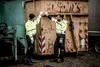 Two men in high-visibility workwear stand next to large industrial containers, giving each other a high-five. Produktbild-Vorschau