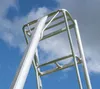 A close-up view of the top section of an aluminum ladder against a blue sky with clouds. Produktbild-Vorschau