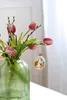 An Easter egg ornament hangs from a tulip stem in a vase. Produktbild-Vorschau
