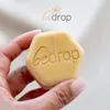 A hand holds a hexagonal bar of soap with the brand name embossed on it. The brand logo is visible at the top of the image. Produktbild-Vorschau