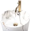 A close-up view of a marble-patterned sink with a gold faucet. Produktbild-Vorschau