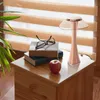 A bedside table with a lamp, books, glasses, and an apple. Produktbild-Vorschau