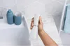 A hand holding a white water flosser over a bathroom sink. Podgląd zdjęcia produktu