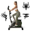 A woman is using a stationary exercise bike, with inset images showing details of the bike. Produktbild-Vorschau