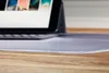 A close-up of a transparent desk mat with a laptop in the background. Produktbild-Vorschau