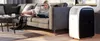 A woman is relaxing on a couch while a portable air conditioner is in the foreground. Produktbild-Vorschau