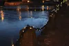A chain with lights draped over rocks next to a body of water at night. Produktbild-Vorschau