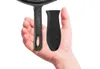 A hand holding a cast iron pan handle and a black silicone handle cover. Produktbild-Vorschau