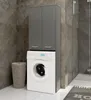 A modern laundry room featuring a white washing machine with a gray cabinet above it, and a wicker laundry basket next to it. Produktbild-Vorschau