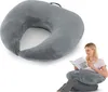 A woman is reading a book while sitting with a U-shaped pillow around her lap. Produktbild-Vorschau