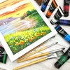 A painting of a landscape with several tubes of acrylic paint and paintbrushes arranged around it. Produktbild-Vorschau