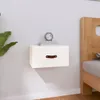 A white floating nightstand with a brown leather handle is mounted on a light gray wall next to a wooden bed frame. Náhľad obrázku produktu