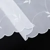 A close-up view of a white sheer curtain with embroidered leaf patterns and a scalloped edge. Produktbild-Vorschau
