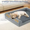 A puppy sleeping on a gray dog bed next to a couch. Voir les images du produit