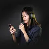 A young woman wearing headphones and holding a smartphone and a microphone, appearing to be singing or recording. Anteprima dell’immagine prodotto