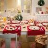 A beautifully set dining table for a festive occasion, likely Christmas, with a red runner, festive tableware, and a small Christmas tree. Produktbild-Vorschau