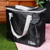 A black cooler bag with white handles sits on a pink blanket on green grass, with a wooden fence in the background. Anteprima dell’immagine prodotto