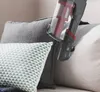 A hand-held vacuum cleaner is being used to clean a sofa with several pillows. Produktbild-Vorschau