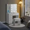 A white vanity table with a lighted mirror and a stool in a room. Voir les images du produit