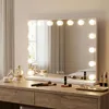 A vanity mirror with lights on a wooden dresser, surrounded by makeup and perfume. Podgląd zdjęcia produktu