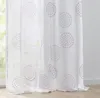 A close-up view of a white sheer curtain with a repeating circular pattern in shades of pink and purple. Produktbild-Vorschau