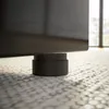 A close-up shot of a black furniture foot resting on a patterned floor. Produktbild-Vorschau